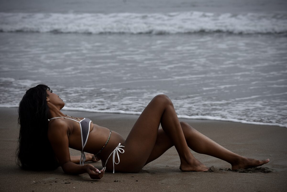 Simone Elise lying on the beach looking toward the ocean